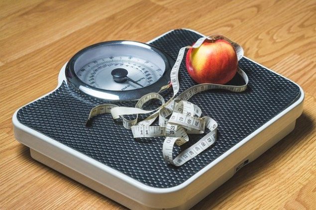 peso con cinta métrica y manzana
